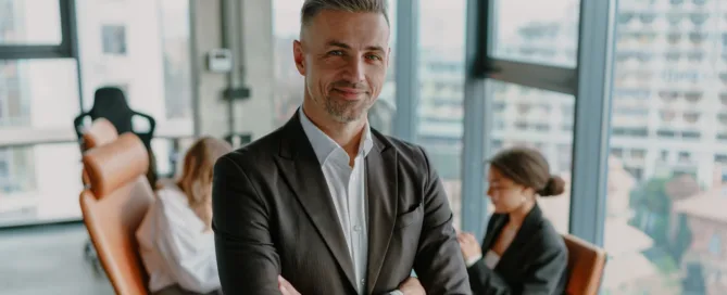smiling-male-entrepreneur-with-crossed-hands-standing-office-banner